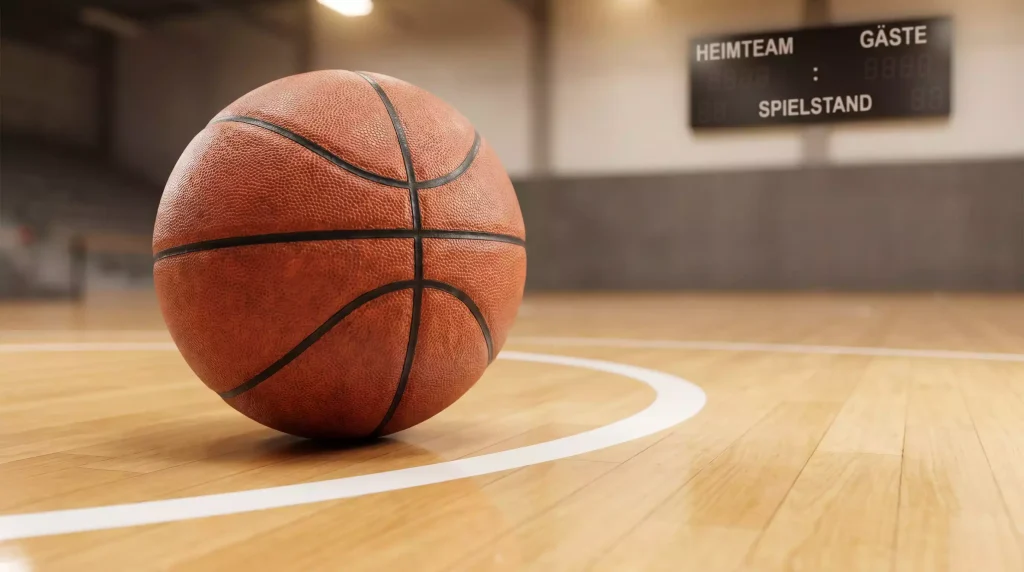 Orangefarbener Basketball liegt auf dem Parkettboden einer NBA-Arena neben der Drei-Punkte-Linie