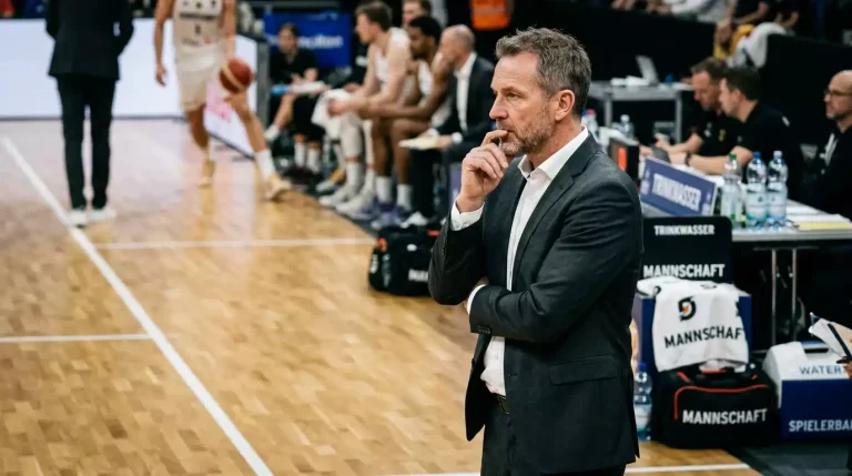 Basketball-Trainer im dunklen Anzug an der Seitenlinie eines NBA-Parketts beobachtet das Spiel